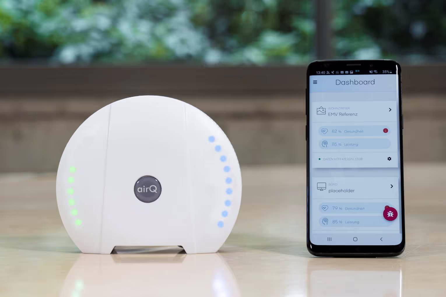 air-Q Luftmessgerät neben Smartphone, auf dem die air-Q Smartphone App geöffnet ist