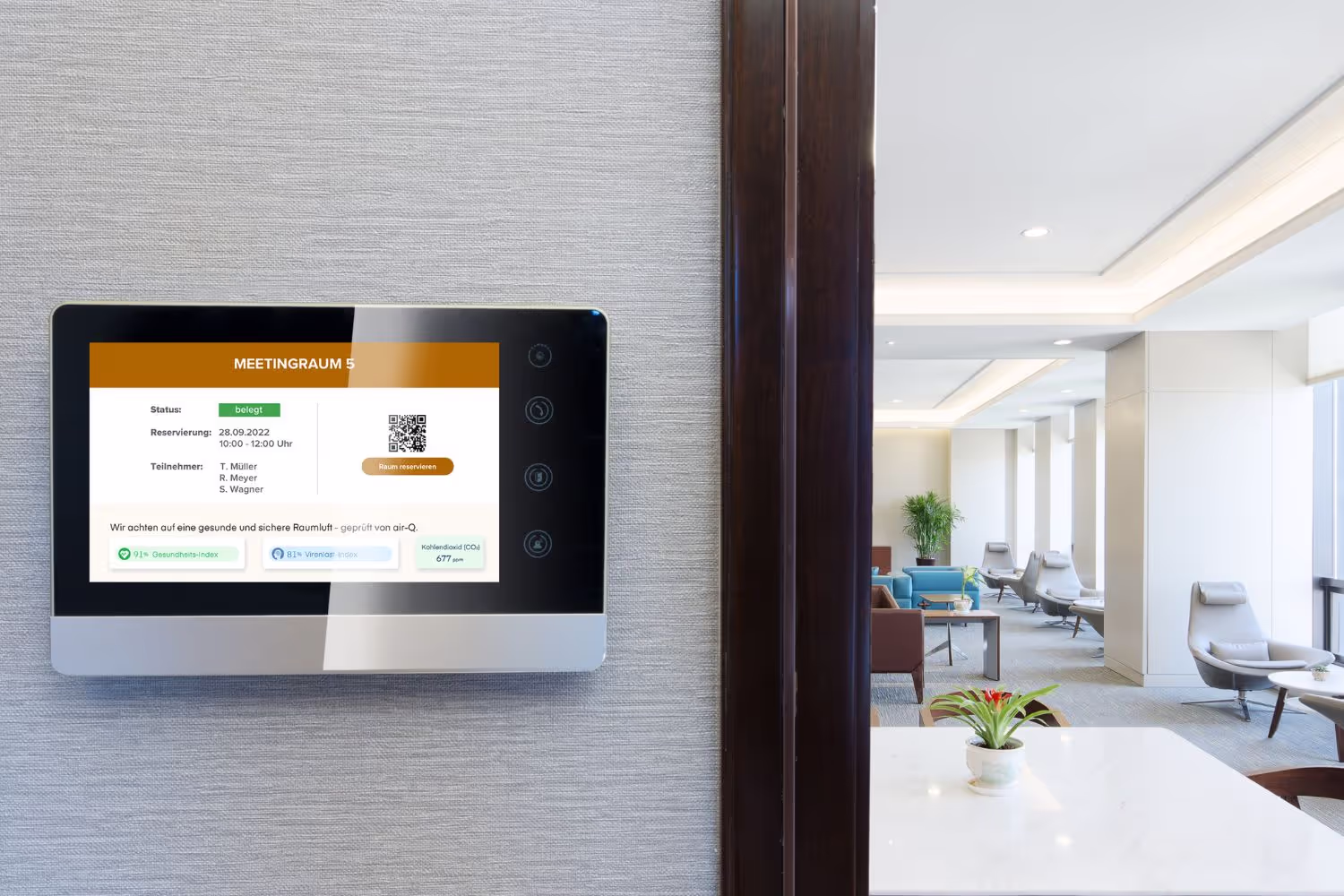 Blick in einen modernen Meetingraum mit Sesseln, links vor der Tür hängt ein Bildschirm, auf dem die Luftqualität per air-Q Smart Widgets angezeigt wird.