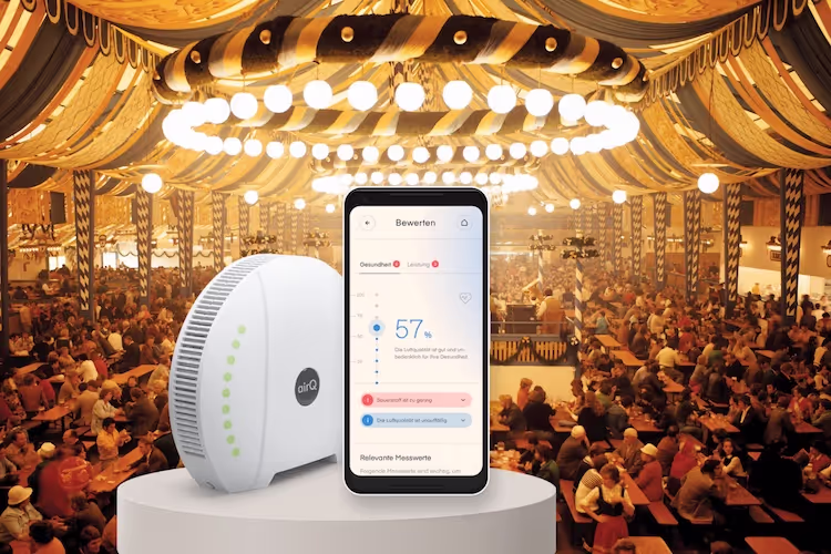 Festzelt Oktoberfest mit Luftmessgerät air-Q und Smartphone mit air-Q App im Vordergrund
