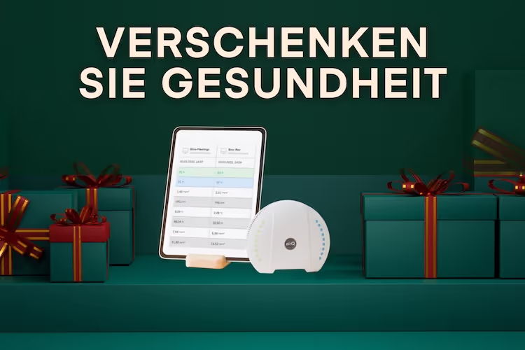 Luftmessgerät air-Q mit Tablet und Luftauswertung neben grünen Weihnachtsgeschenken
