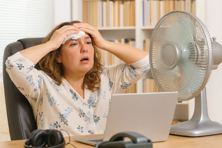 Hitze im Büro - Frau schwitzt